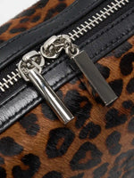 Close-up of silver-tone dual zipper pulls and black cowhide trim