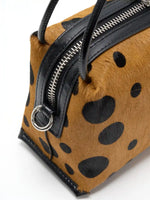 Close-up of silver-tone side ring, black cowhide trim, and hair-on hide exterior