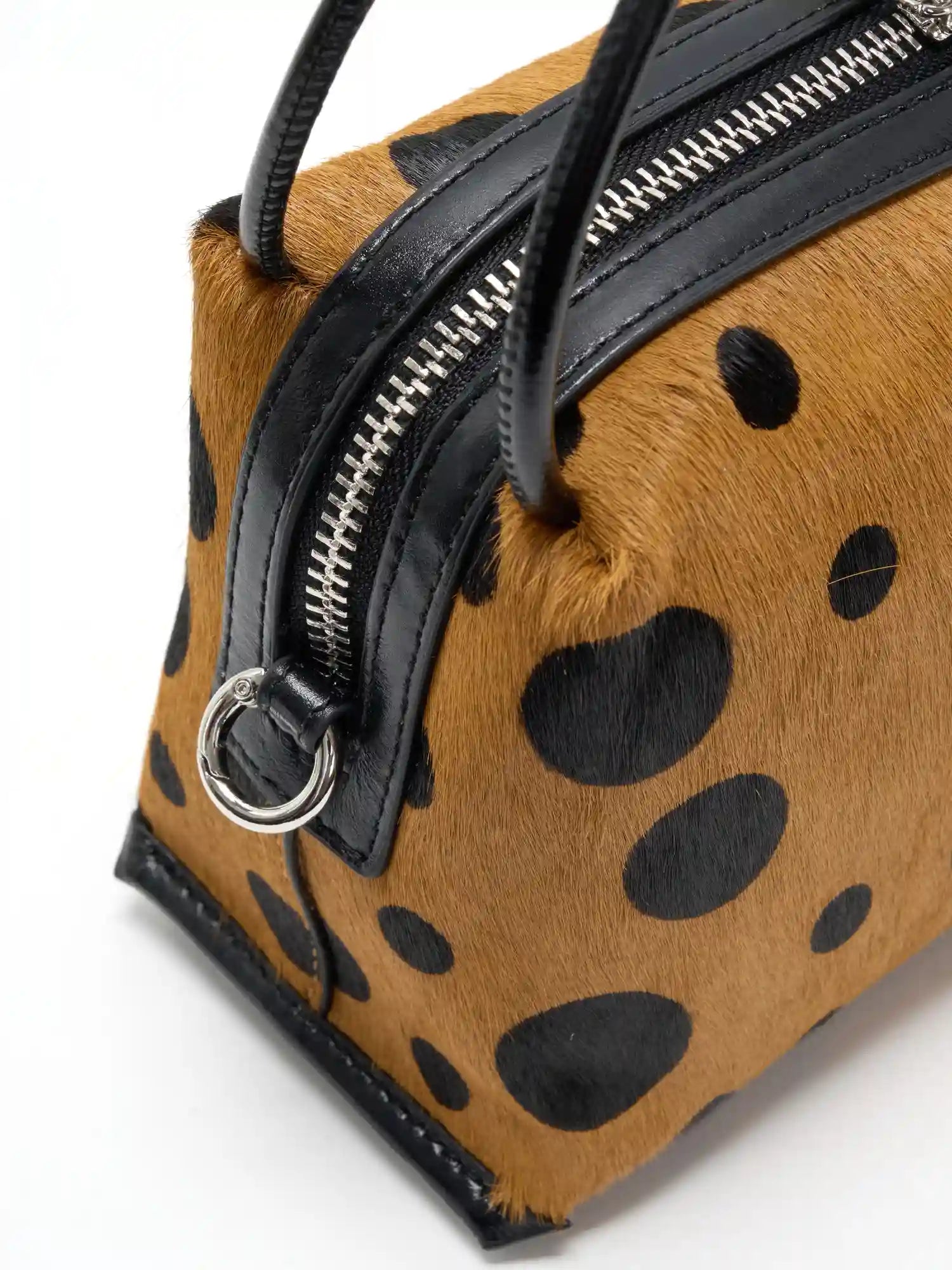 Close-up of silver-tone side ring, black cowhide trim, and hair-on hide exterior