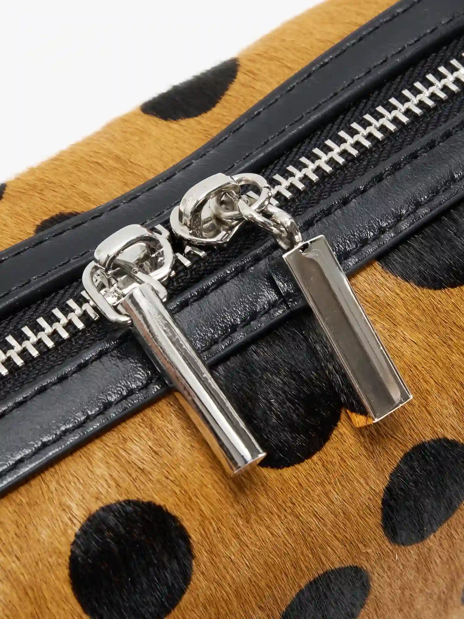 Close-up of silver-tone dual zipper pulls and black cowhide trim