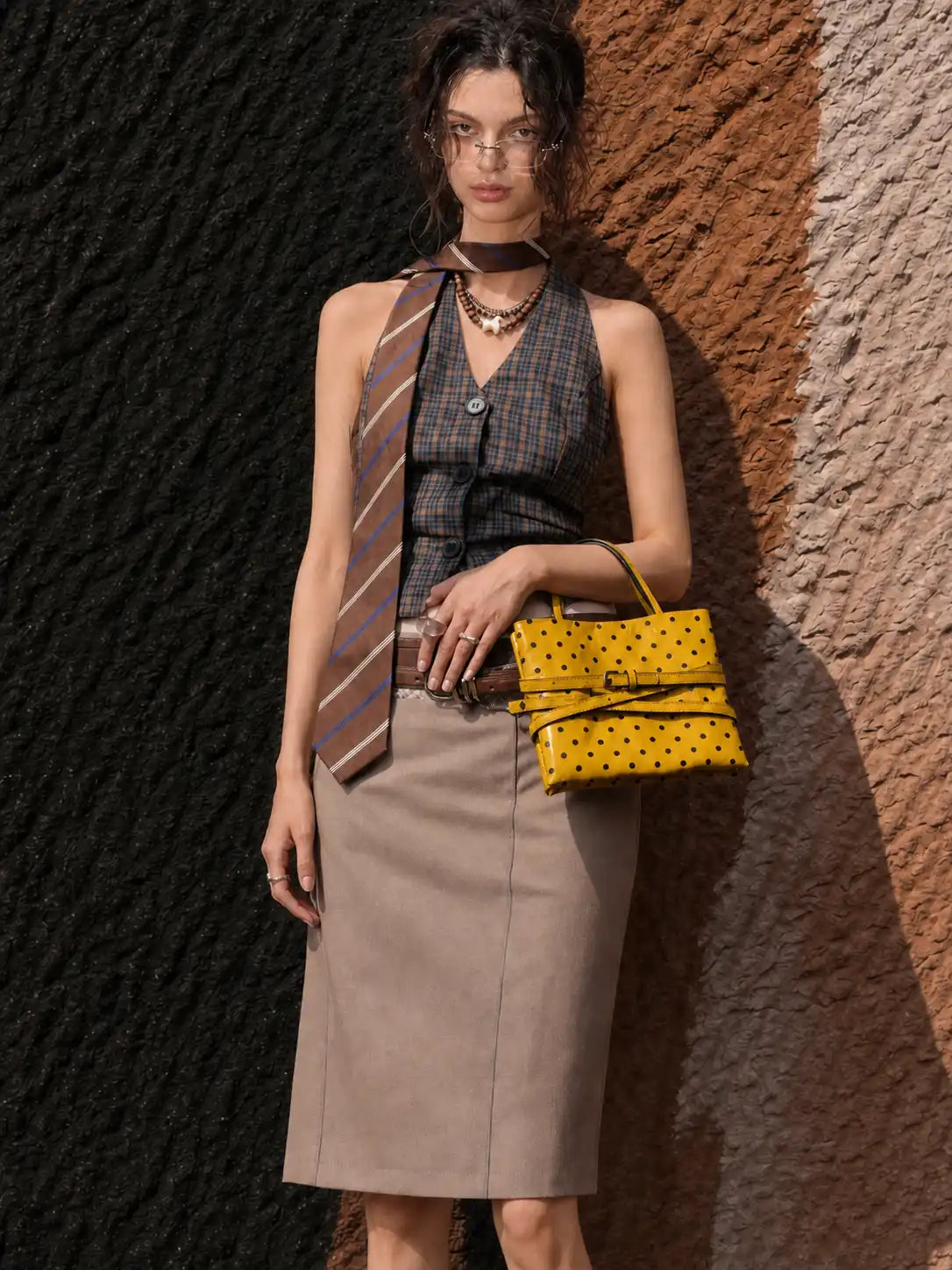 Model carrying the small yellow polka-dot square bag by its top handles