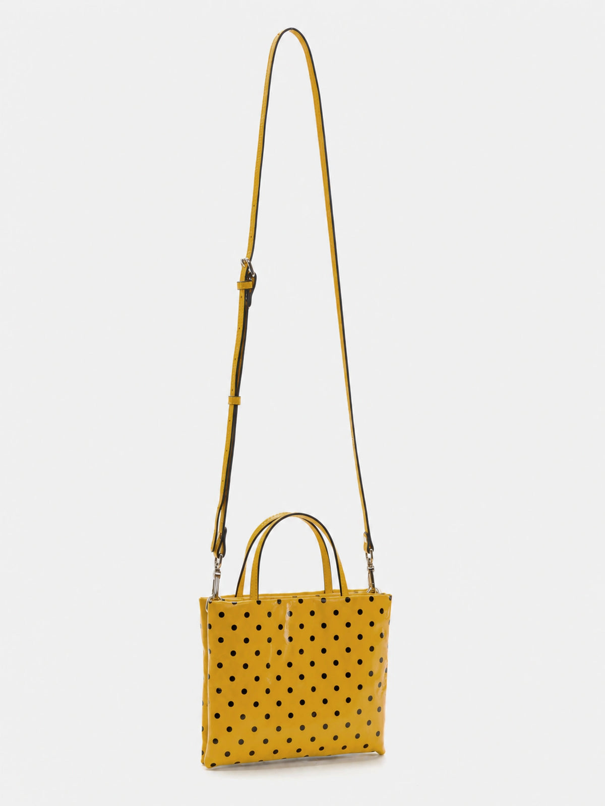 Small yellow polka-dot square bag rear view with adjustable crossbody strap attached