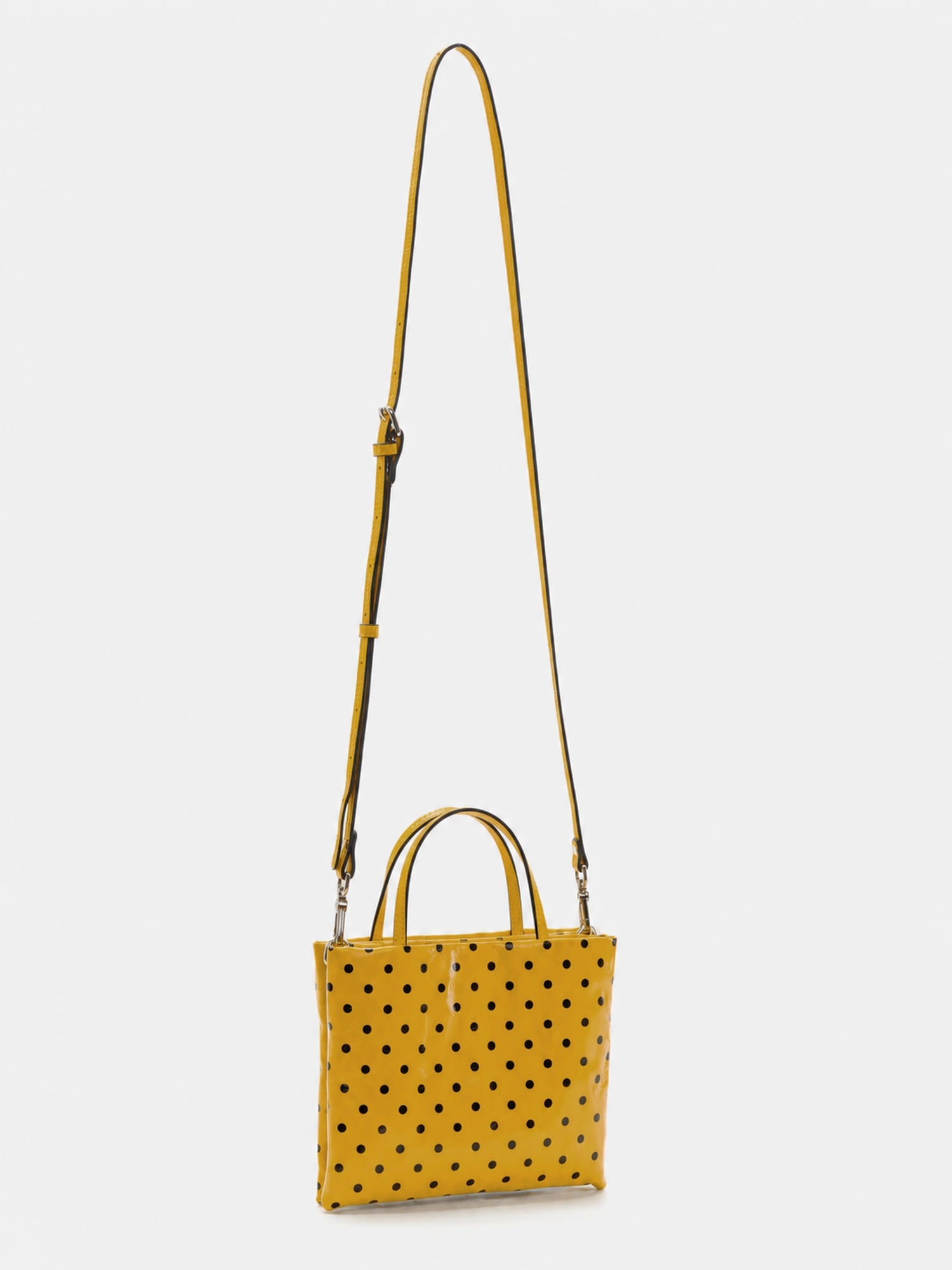 Small yellow polka-dot square bag rear view with adjustable crossbody strap attached