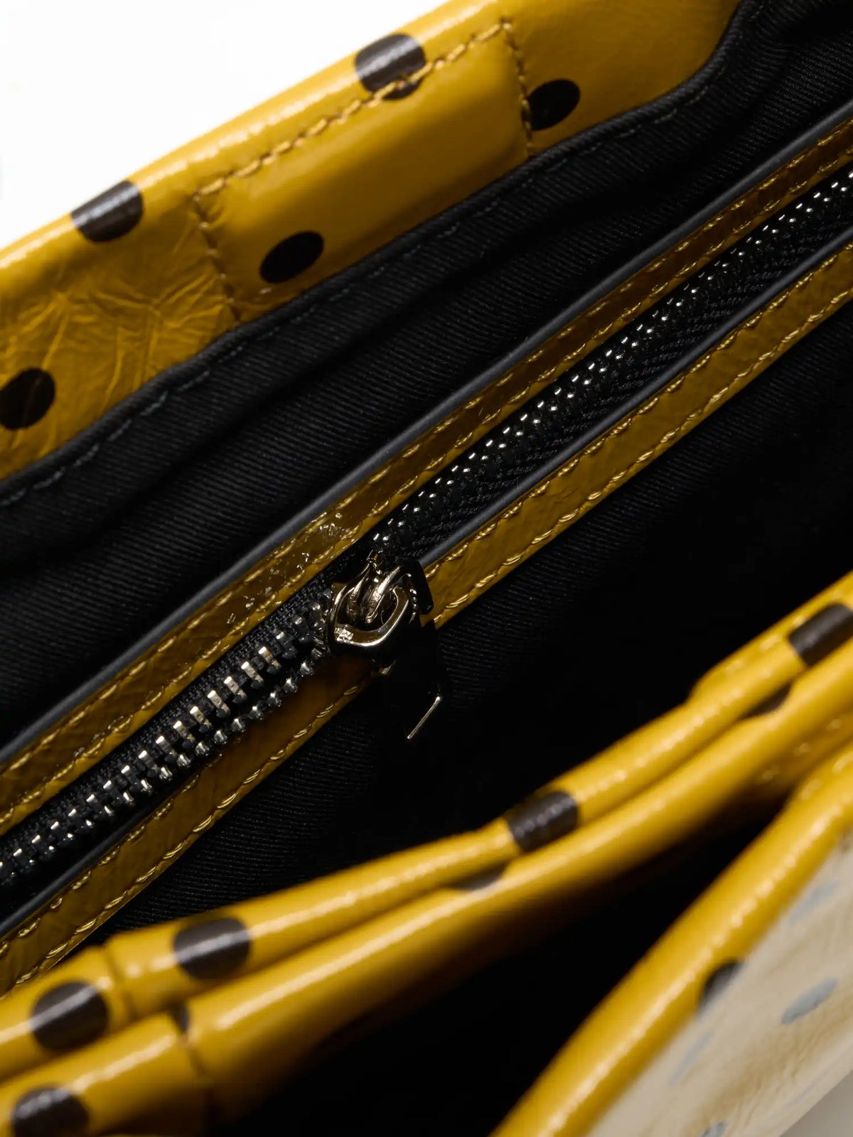 Fabric-lined interior zip pocket inside the yellow polka-dot square bag