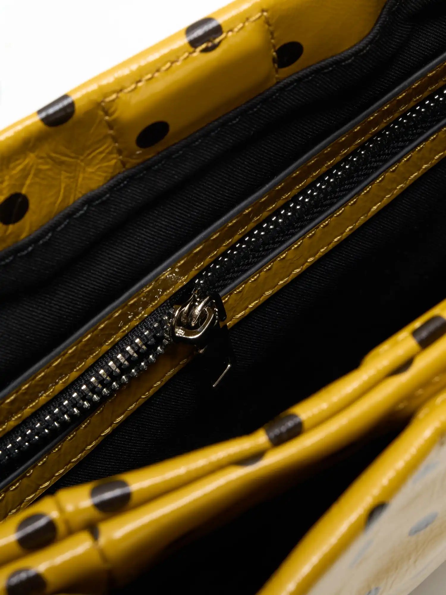 Fabric-lined interior zip pocket inside the yellow polka-dot square bag