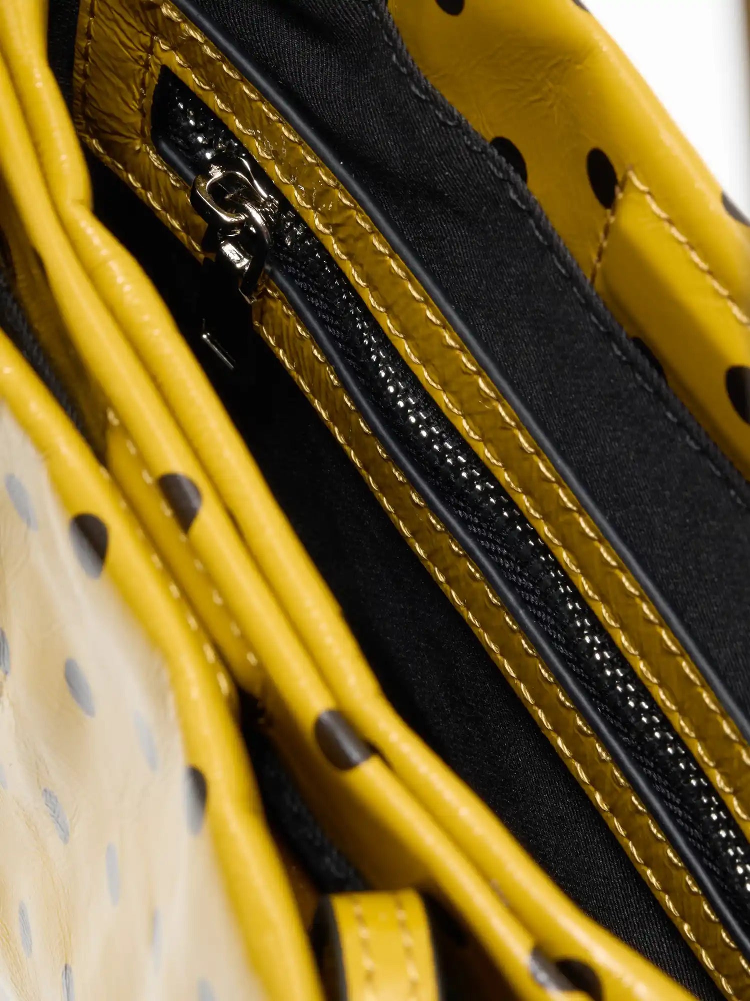 Two-zone fabric-lined interior of the yellow polka-dot square bag