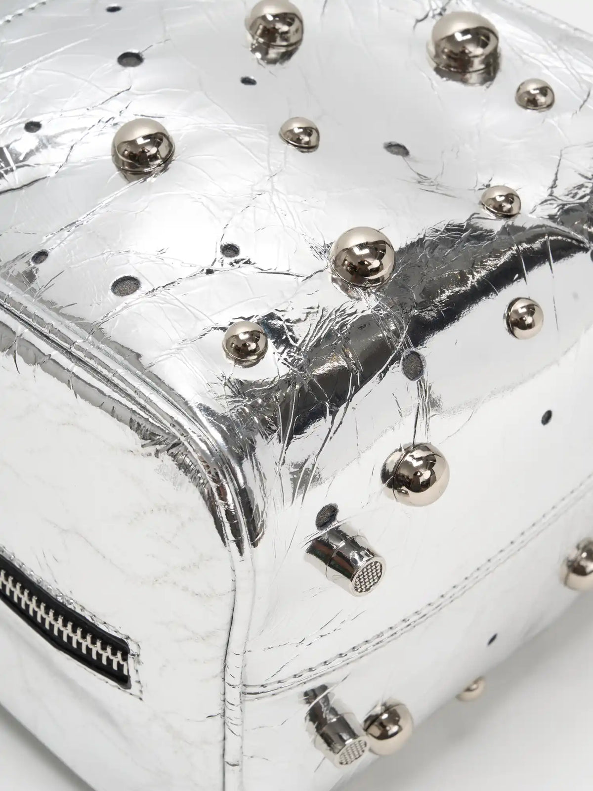 Mixed-size silver-tone dome studs on metallic cowhide close-up