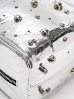 Mixed-size silver-tone dome studs on metallic cowhide close-up