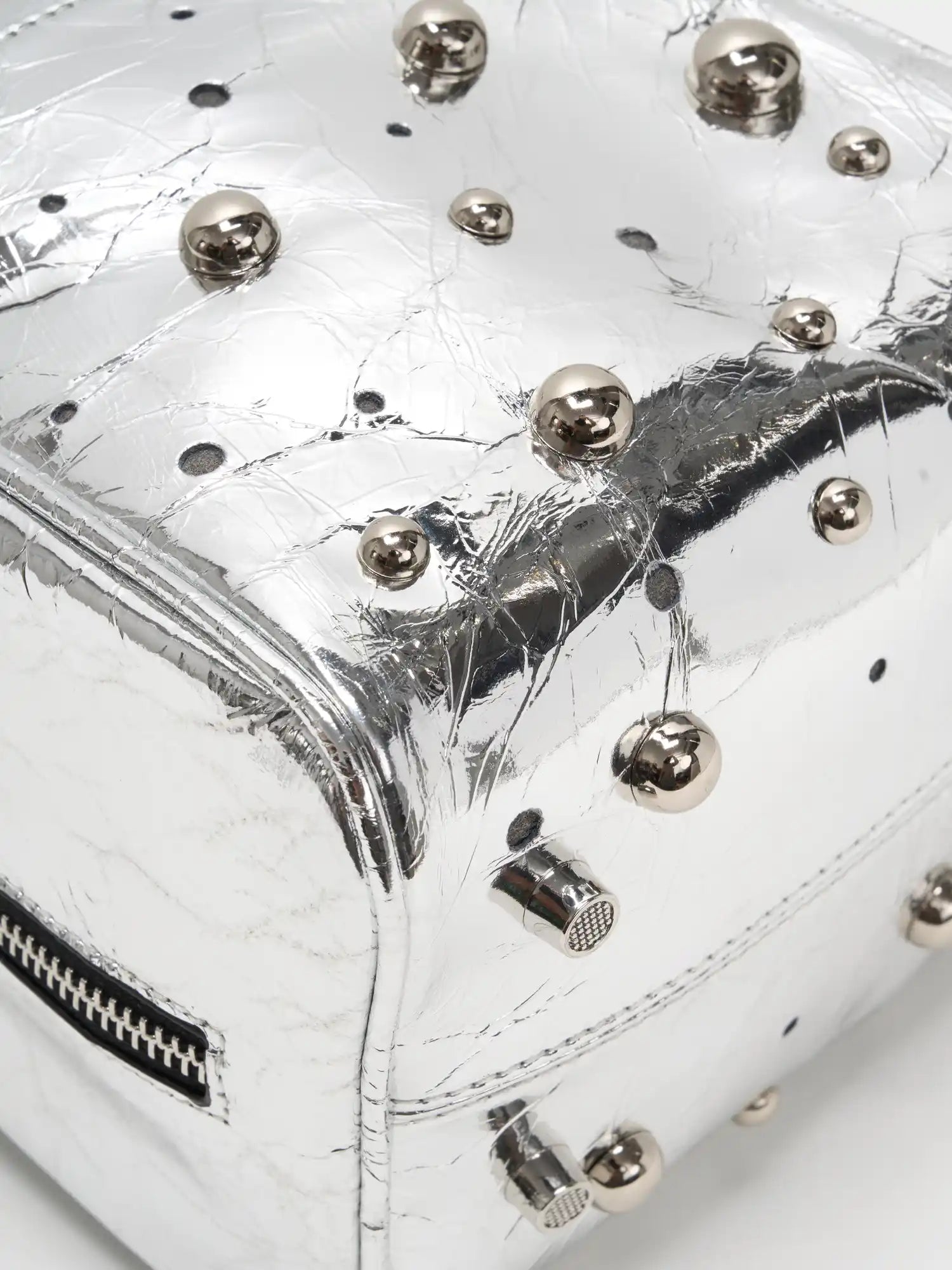 Mixed-size silver-tone dome studs on metallic cowhide close-up