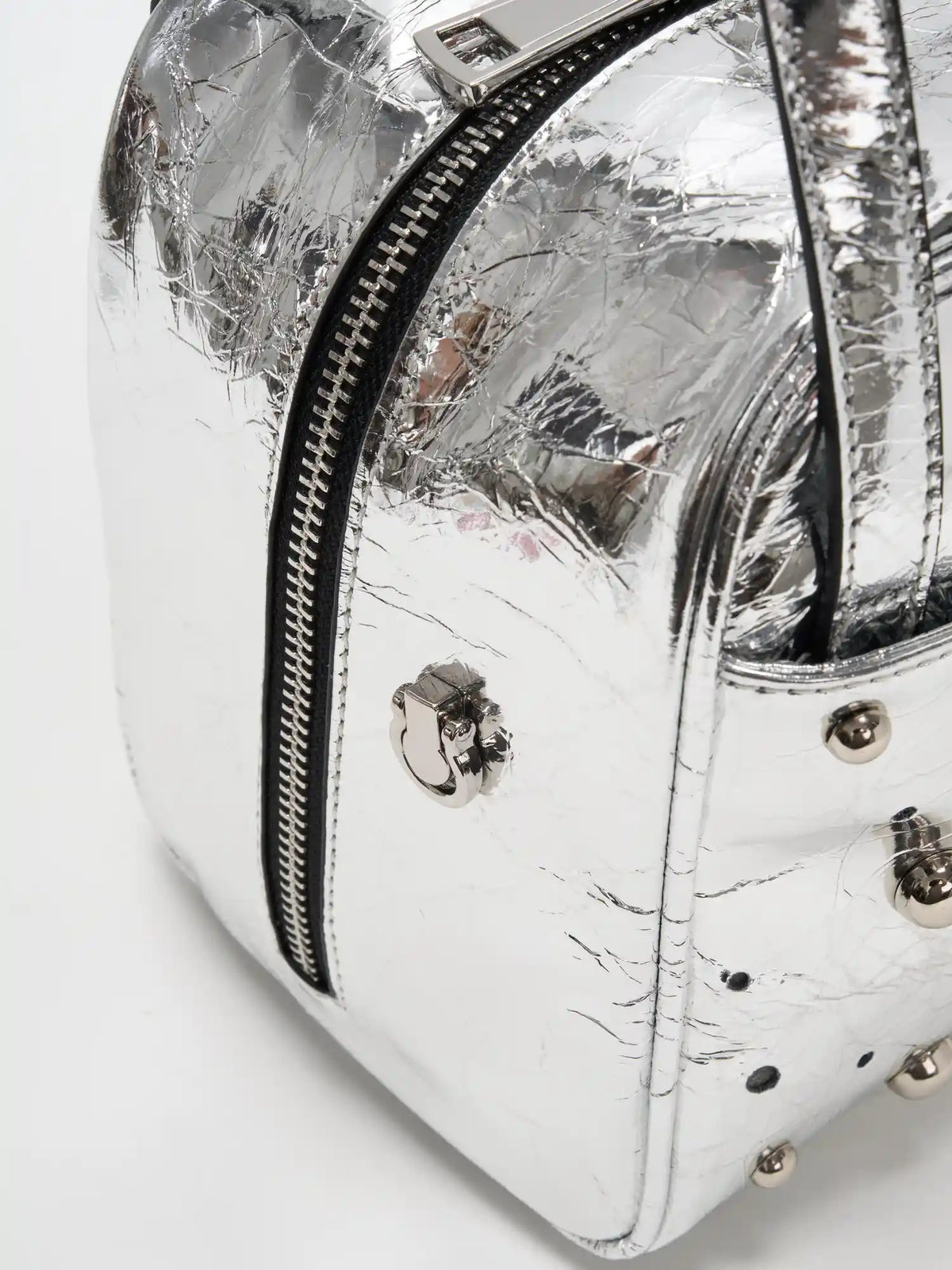Near-wraparound side zipper and scattered stud detail on the silver cube bag