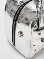Near-wraparound side zipper and scattered stud detail on the silver cube bag