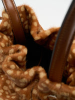 View into the dark interior through the gathered opening of the fawn-spotted bag