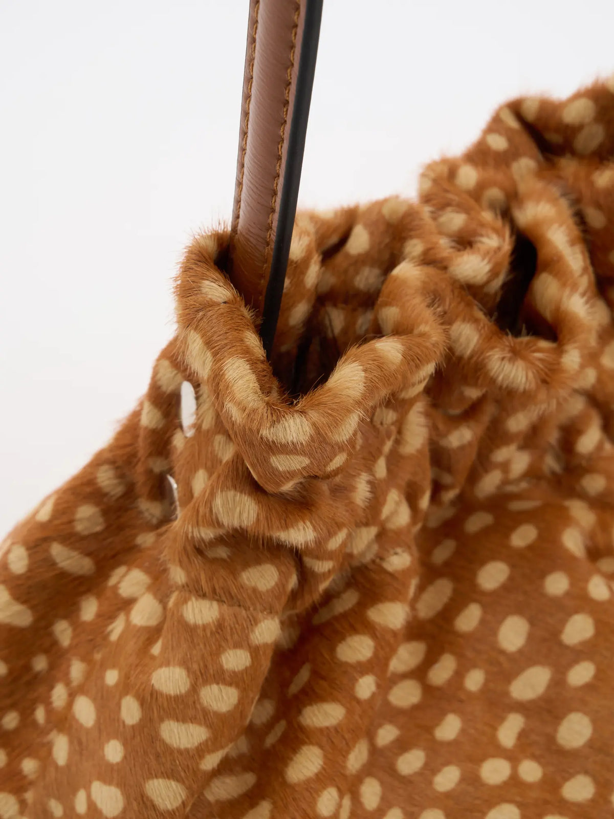Close-up of gathered fawn-spotted hair-on top and stitched brown shoulder strap