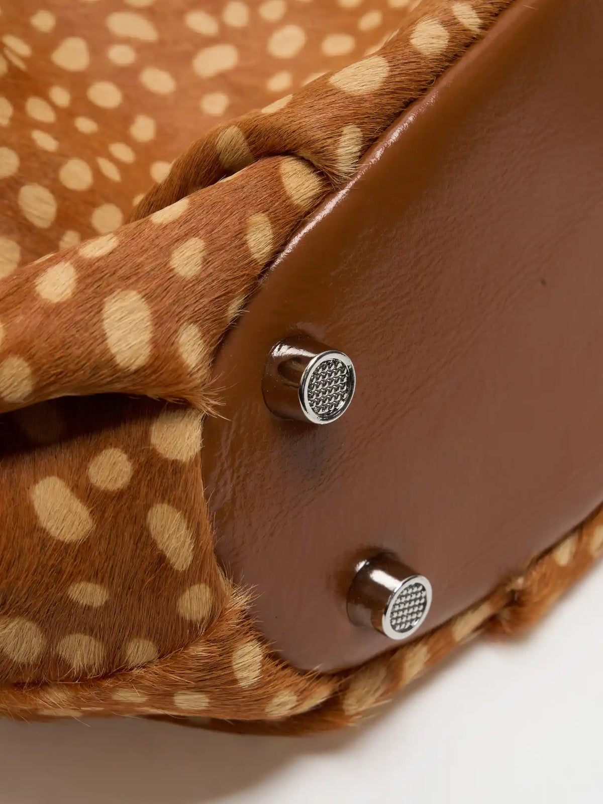 Brown base panel and silver-tone metal feet on the fawn-spotted shoulder bag