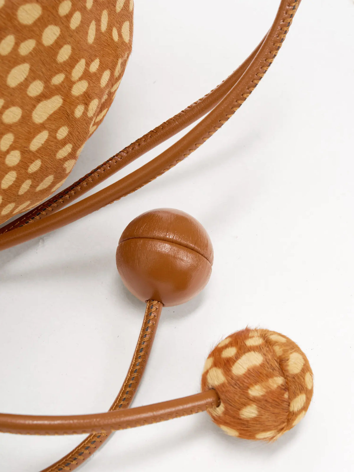 Smooth brown sphere and matching fawn-spotted sphere on the drawstring ends