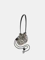 Side angle of rounded zebra-print bag with extended drawstrings and two spheres