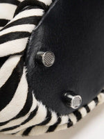 Black base panel and silver-tone metal feet on the zebra-print shoulder bag