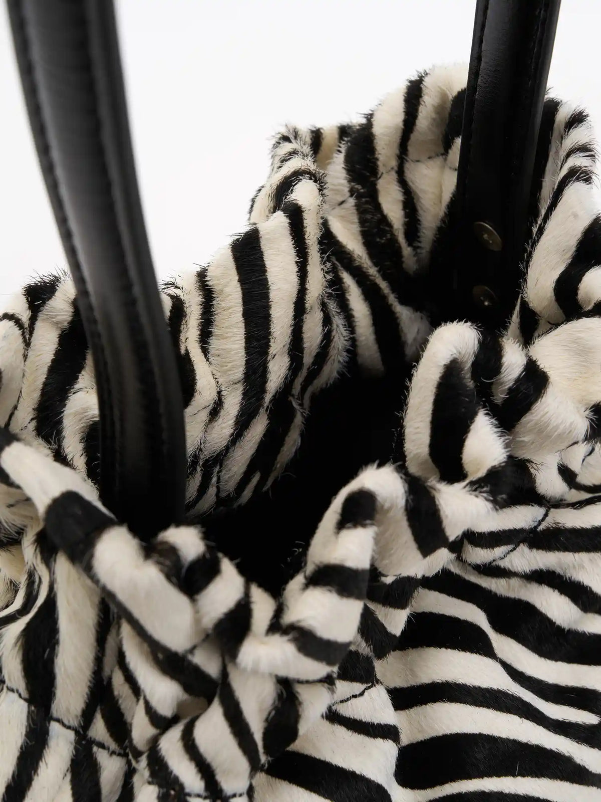 View into the dark interior through the gathered top of the zebra-print bag