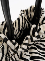View into the dark interior through the gathered top of the zebra-print bag