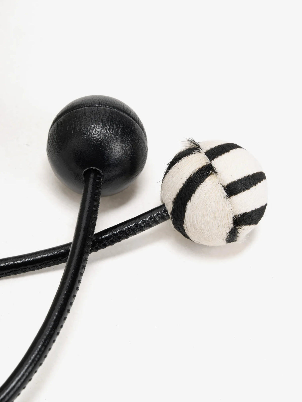 Smooth black sphere and matching zebra-print sphere on the drawstring ends