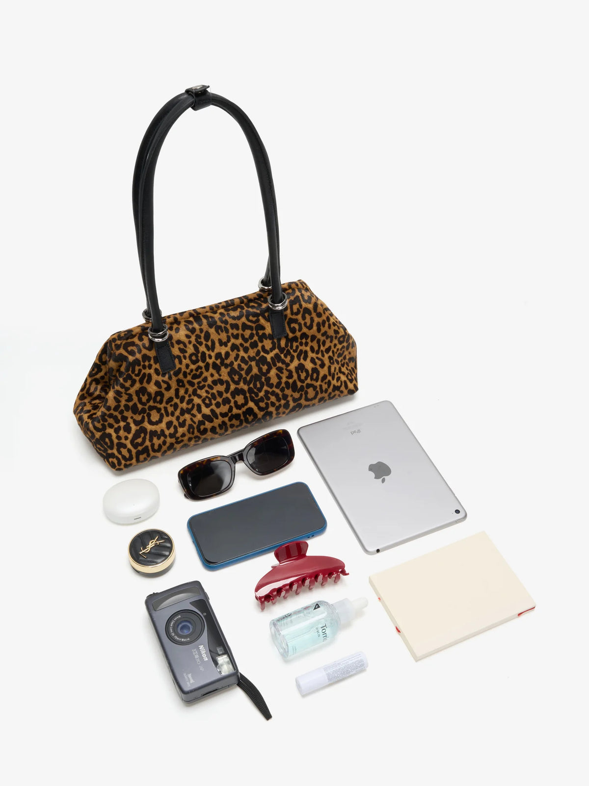 Leopard frame bag displayed with tablet phone sunglasses camera and daily essentials