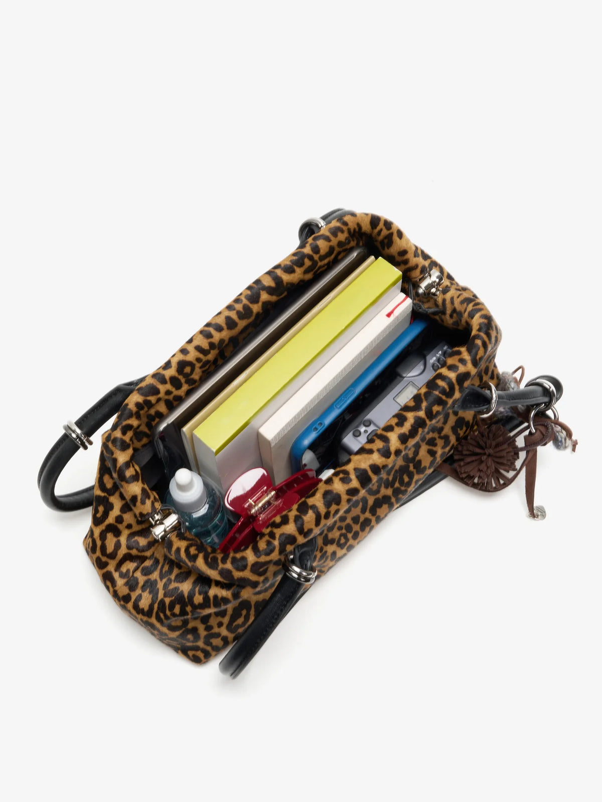 Open leopard shoulder bag packed with tablet notebooks and daily essentials