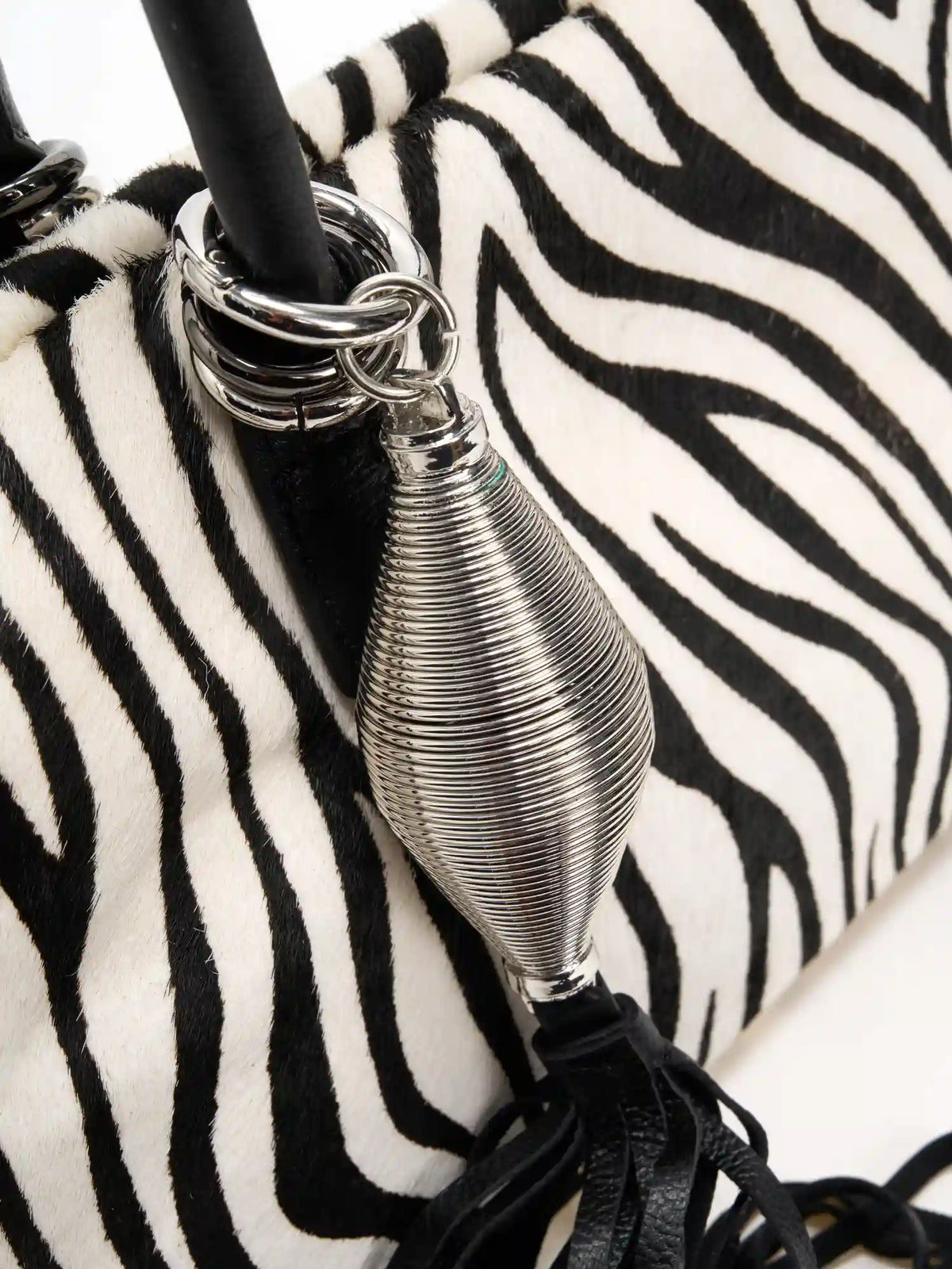 Bright silver tassel charm and stacked handle rings on zebra hide