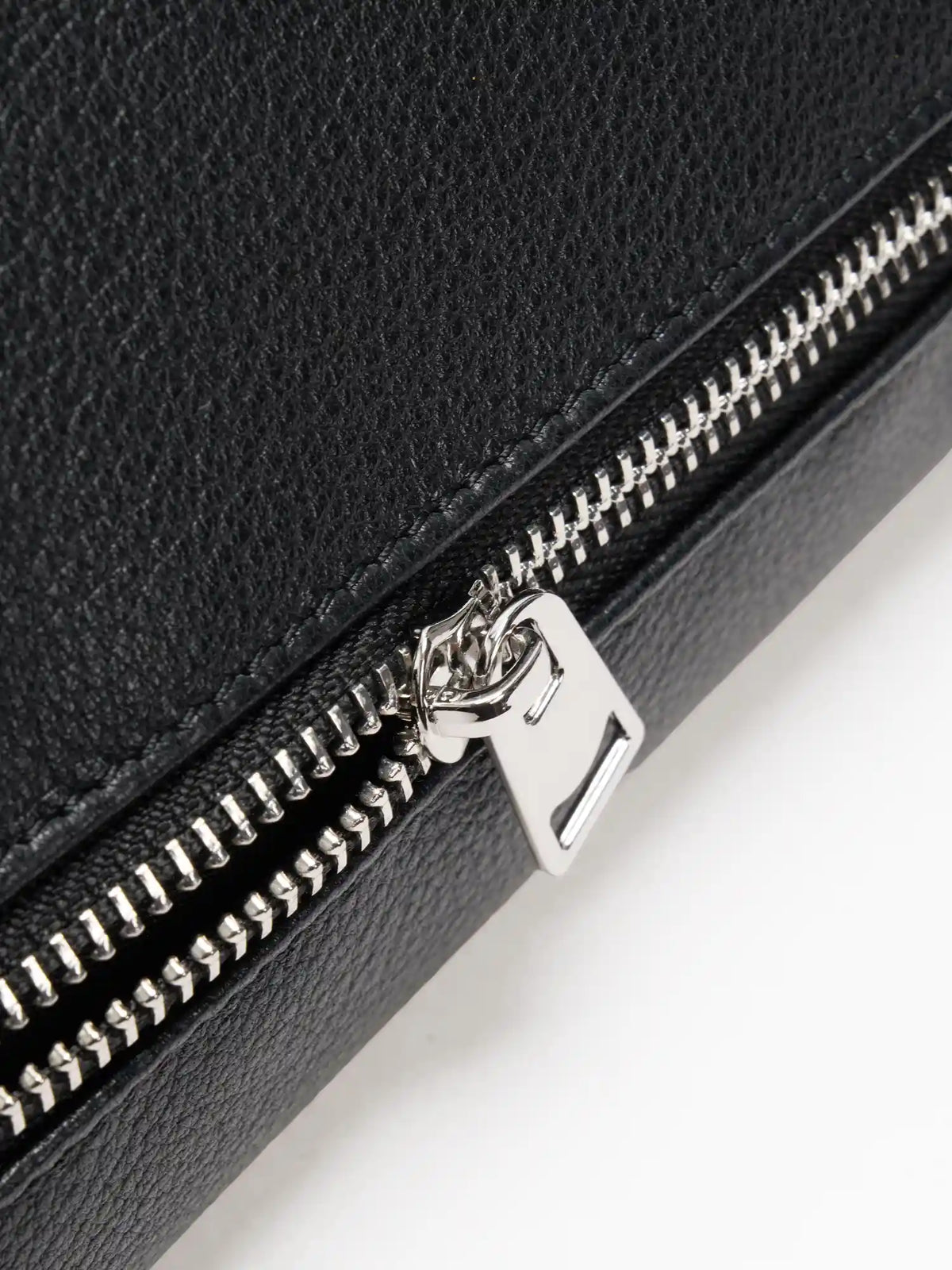 Silver-tone exterior zipper on fine-grain black leather close-up