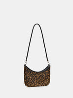 Angled view of a leopard crescent shoulder bag showing its slim profile and curved zip opening