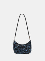 Front view of a dark hair-on hide crescent bag with pale blue spots and a short black shoulder strap