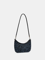 Angled view of a blue-spotted crescent shoulder bag showing its curved opening and slim profile