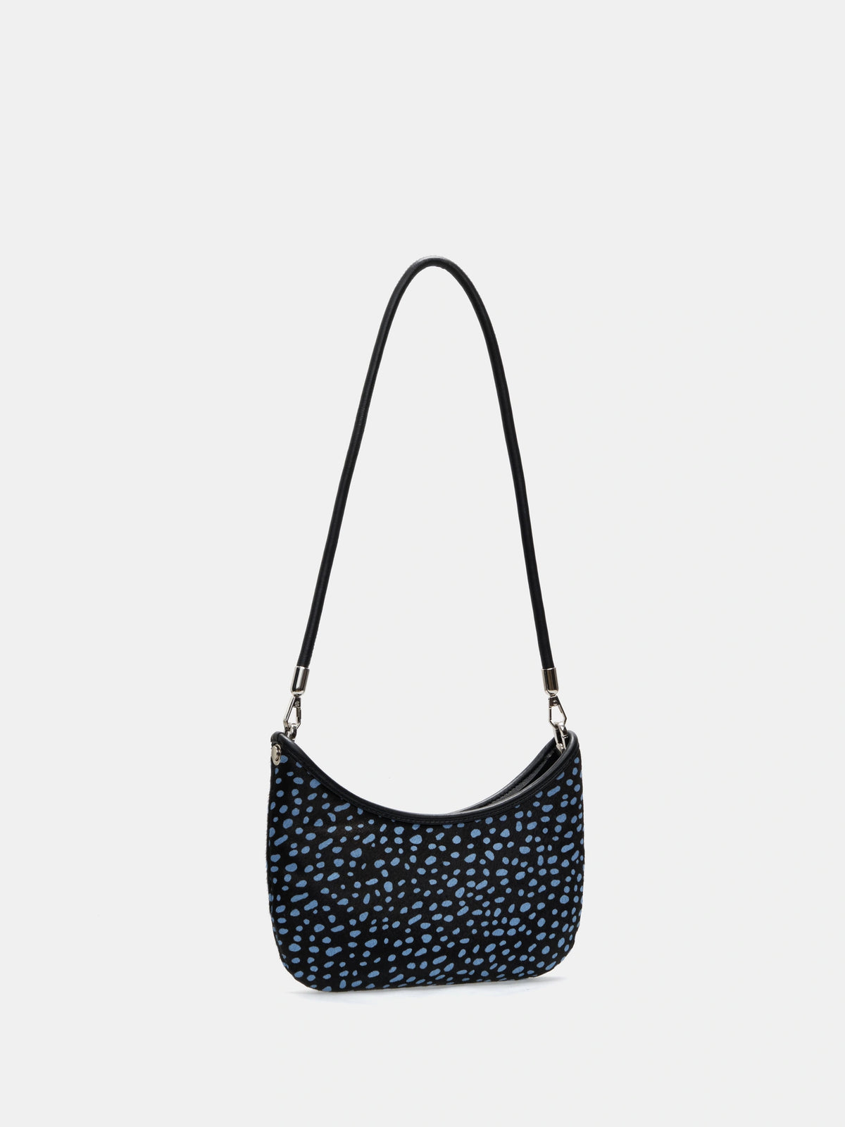Angled view of a blue-spotted crescent shoulder bag showing its curved opening and slim profile