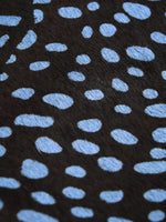 Close-up of irregular pale blue spots on the dark hair-on hide surface