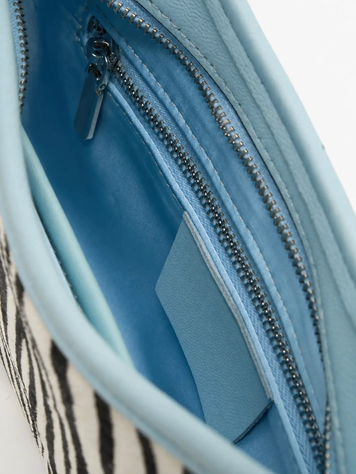 Close-up of the blue fabric lining and interior zip pocket in the Ice Zebra bag