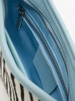 Close-up of the blue fabric lining and interior zip pocket in the Ice Zebra bag