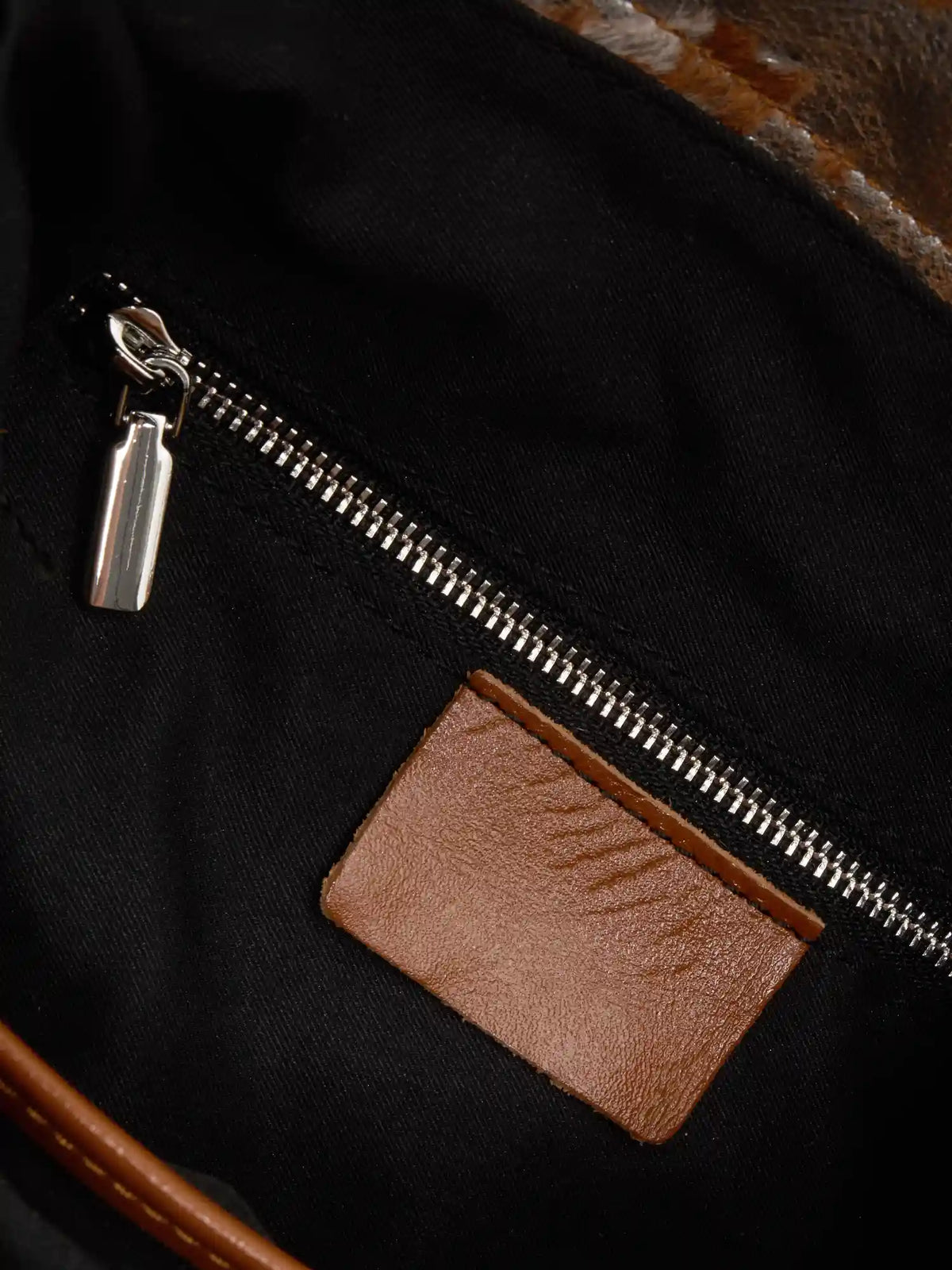 Black fabric lining and interior zip pocket of Gilded Caramel bucket bag