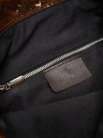 Black fabric lining and interior zip pocket with brown leather tab inside Mocha Cow Print bag