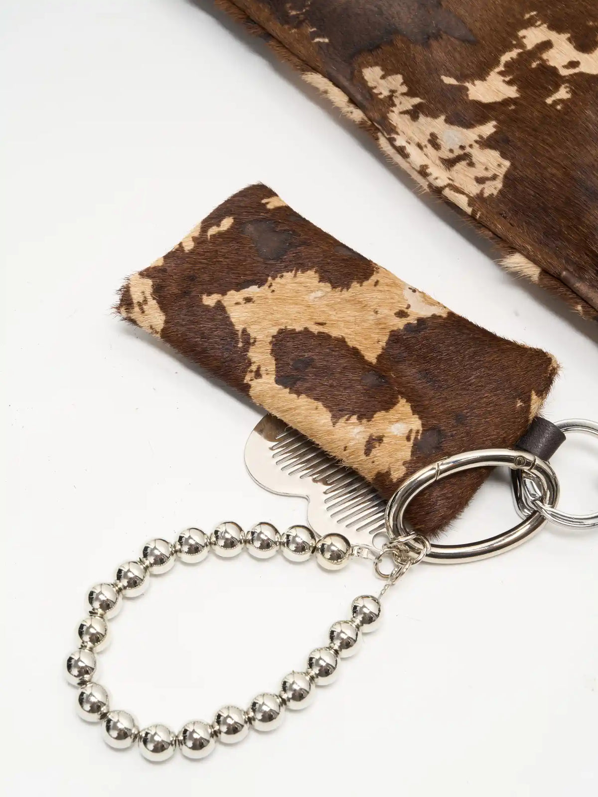 earthy print, silver accents detail of The Painted Charm Slim Bucket Bag - Mocha Cow Print
