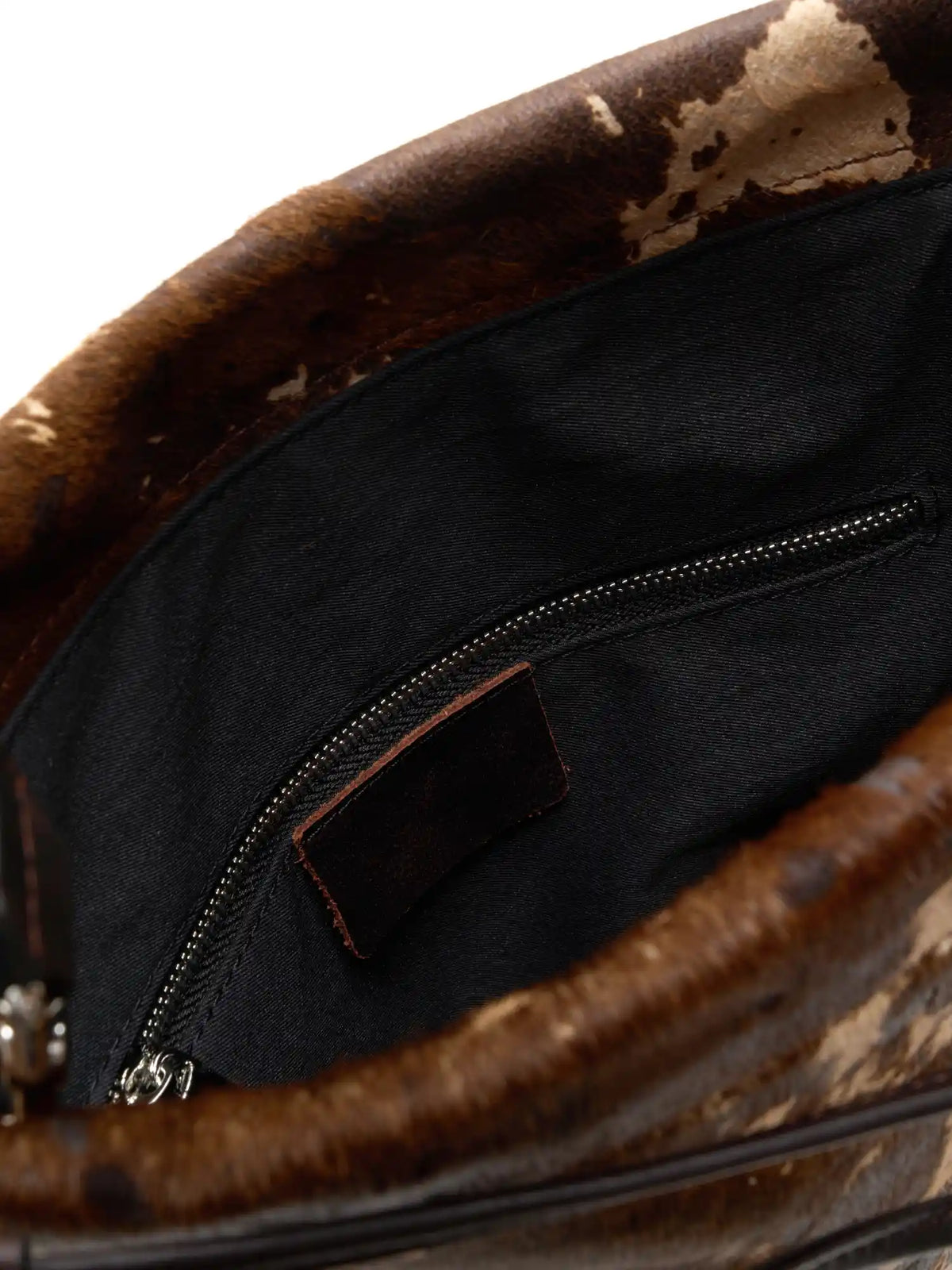 organized inside detail of The Painted Charm Slim Bucket Bag - Mocha Cow Print