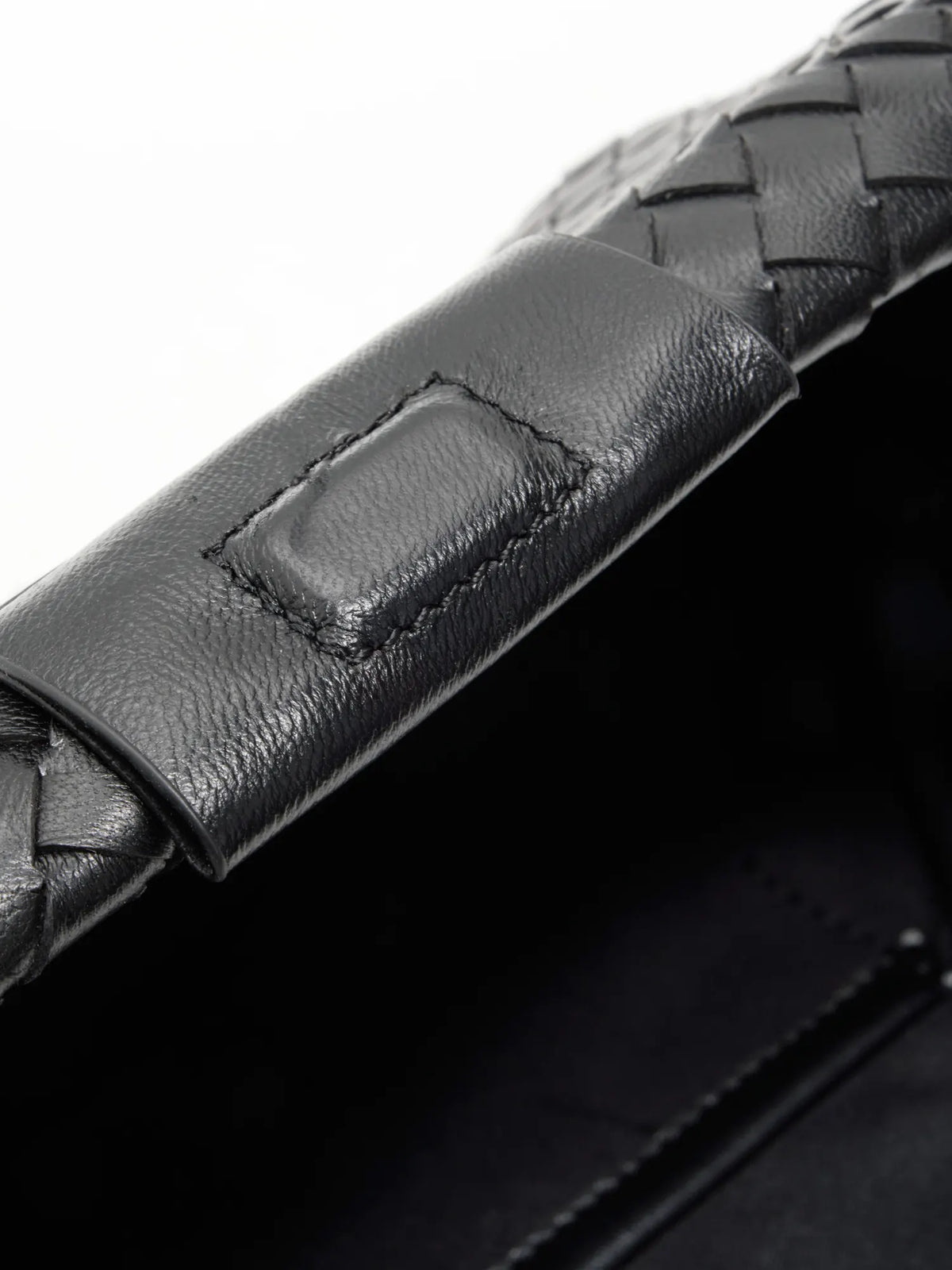 Black Weave handwoven sheepskin chain baguette bag close-up of the leather tab and frame edge
