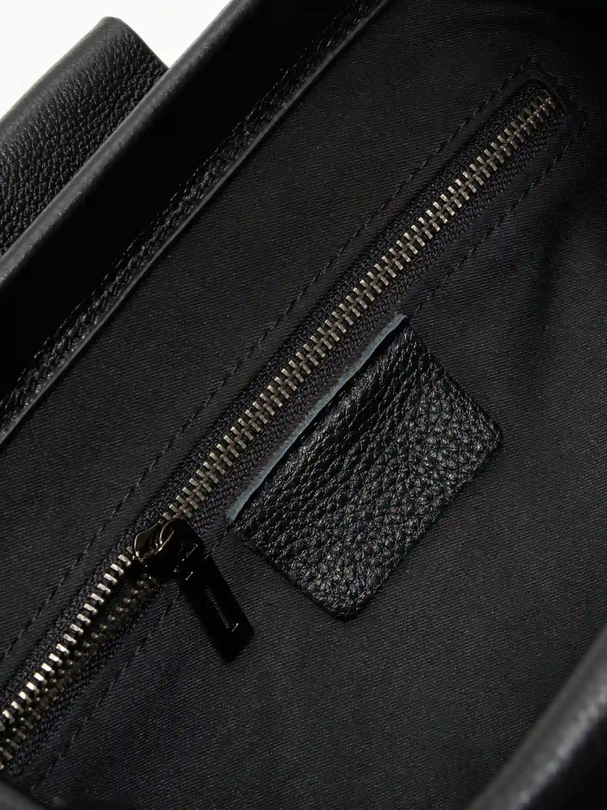Pebbled Black cowhide chain baguette bag close-up of the interior zip pocket and pebbled leather trim