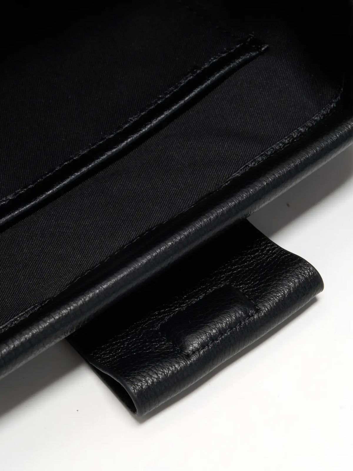 Pebbled Black cowhide chain baguette bag close-up of the interior slip pocket and magnetic tab