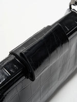 Black Croc cowhide chain baguette bag close-up of the matching magnetic tab and framed top