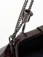 Burgundy Croc cowhide chain baguette bag close-up of the adjustable chain fitting and glossy frame edge