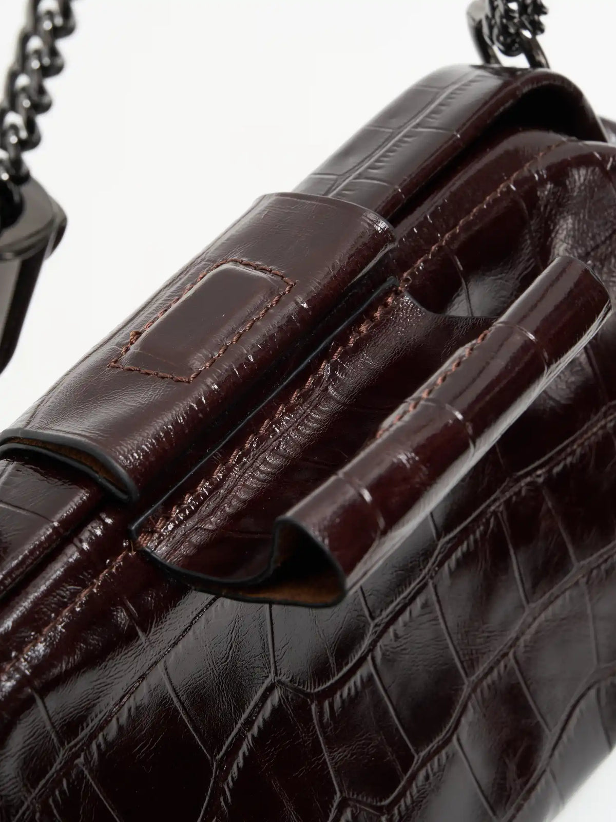 Burgundy Croc cowhide chain baguette bag close-up of the matching magnetic tab and framed top