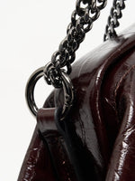 Burgundy Croc cowhide chain baguette bag close-up of the polished chain links and side ring